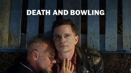 Two people are lying on a blue block palette. The one on the right stares up contemplatively past the camera as the one on the left lies on the right one's shoulder, their eyes closed, cuddling the person on the right with their hand on their chest. The person on the right has short brown hair with faded sides. They are wearing a red and black flannel and a black leather jacket. The person on the left has their eyes closed, a goatee and light brown short hair with faded sides. They are wearing a navy blue polo with a thin white line at the edge of their collar.