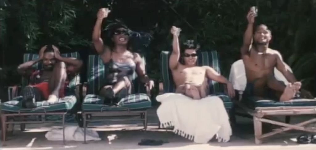 Still from Punks (2000). Four people sit in reclining outdoor chairs; three hold their cups up in salutations while the fourth holds their hands over their ears. The person on the far left has dark brown, a buzz cut with black hair, and wearing red swimsuit bottoms and no top.The person to the right of them has brown skin and is wearing sunglasses, a one piece, and a beach hat. The person to their right has light skin sunglasses, short black hair and light coloured swimsuit bottoms but no top. The person on their right has brown skin and short black hair, not wearing a top and crossing their legs.